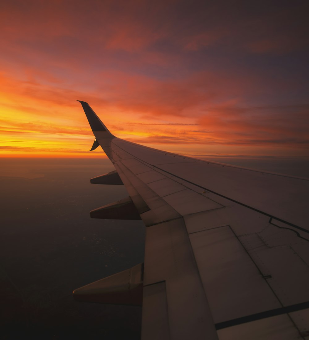 Airplane wing above the clouds at sunset
