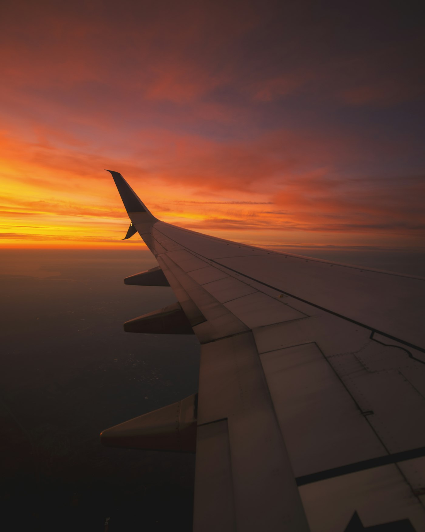 Airplane wing above the clouds at sunset